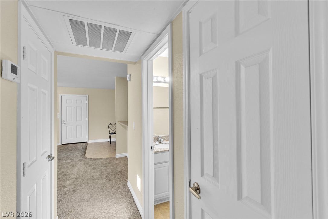 A classic hallway transitions smoothly from soft carpeting to a tiled bathroom entry.