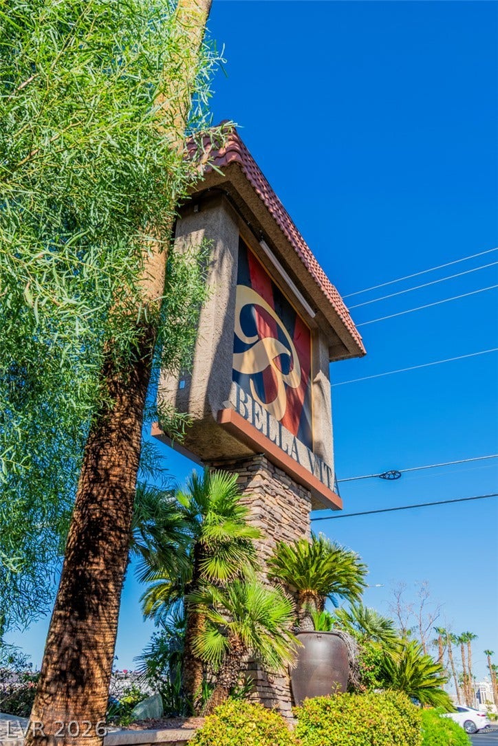A prominent community sign rises above manicured desert landscaping against a clear blue sky.