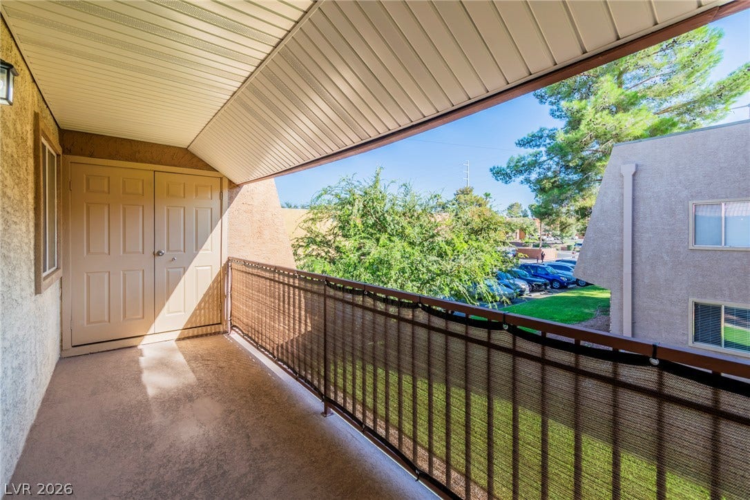 A private covered balcony looks out over the surrounding neighborhood trees.