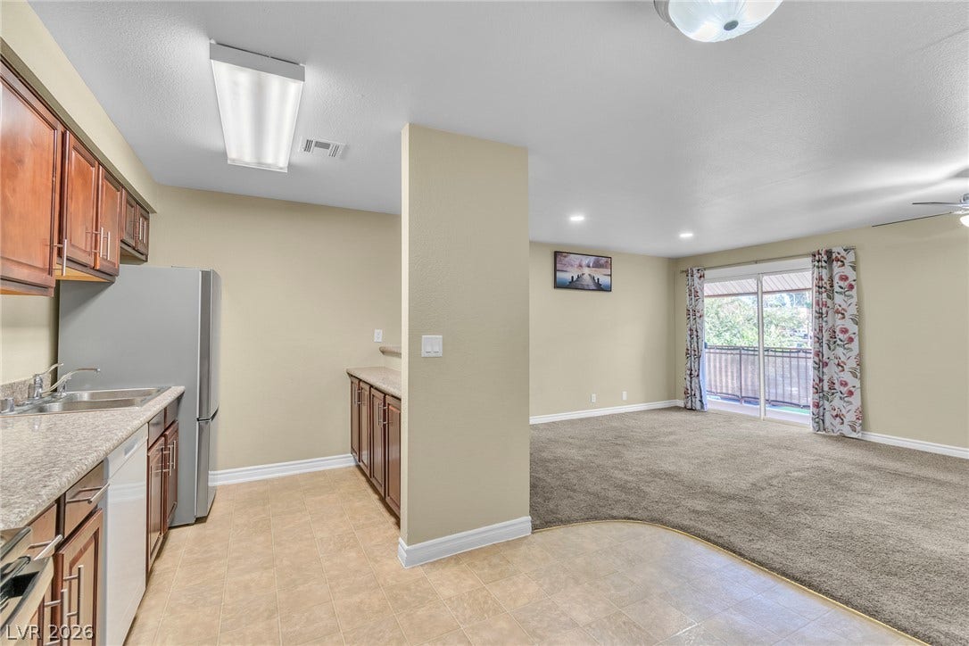 An open floorplan seamlessly connects the functional kitchen area to the carpeted living space.