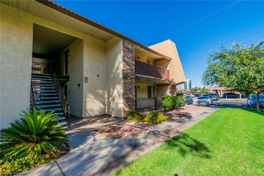 Textured stucco and stone accents define the exterior facade alongside a grassy front lawn.