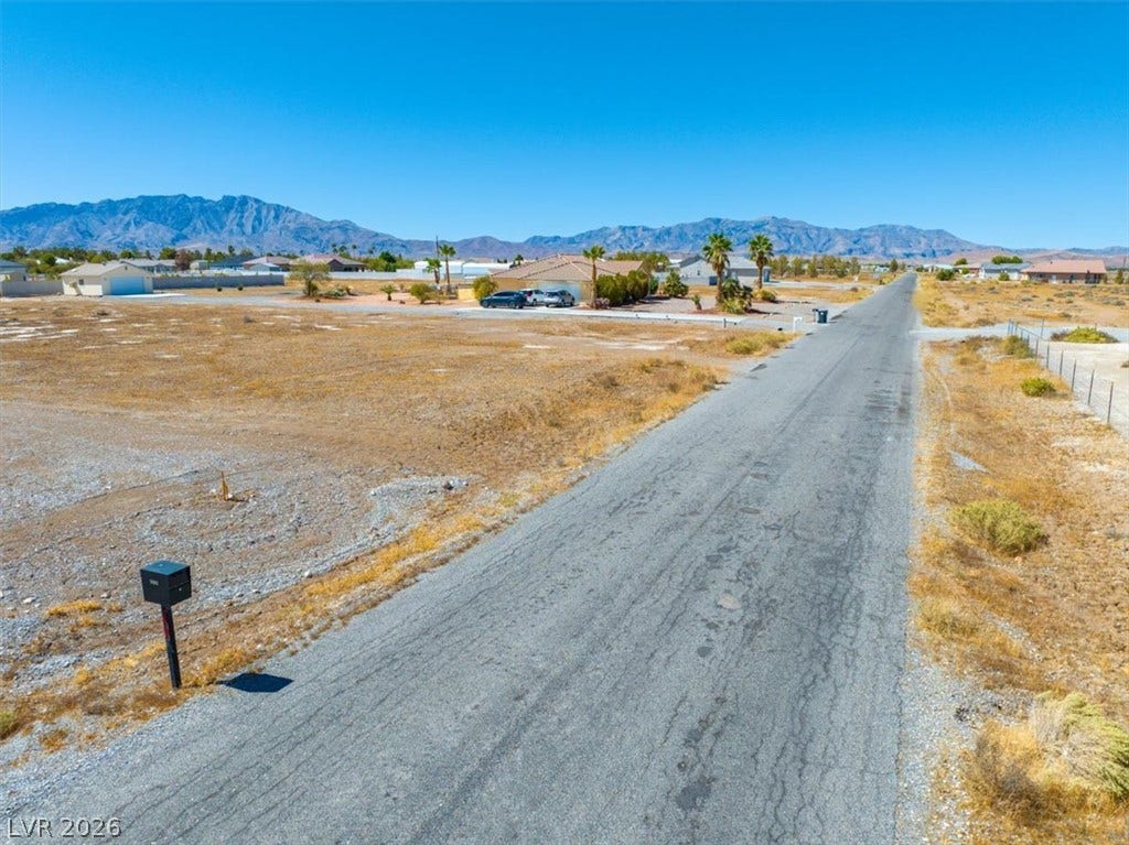 1641 W Huckleberry Street, Pahrump, NV 89048 Dramatic mountain peaks frame a sprawling desert landscape bordering a quiet paved road.