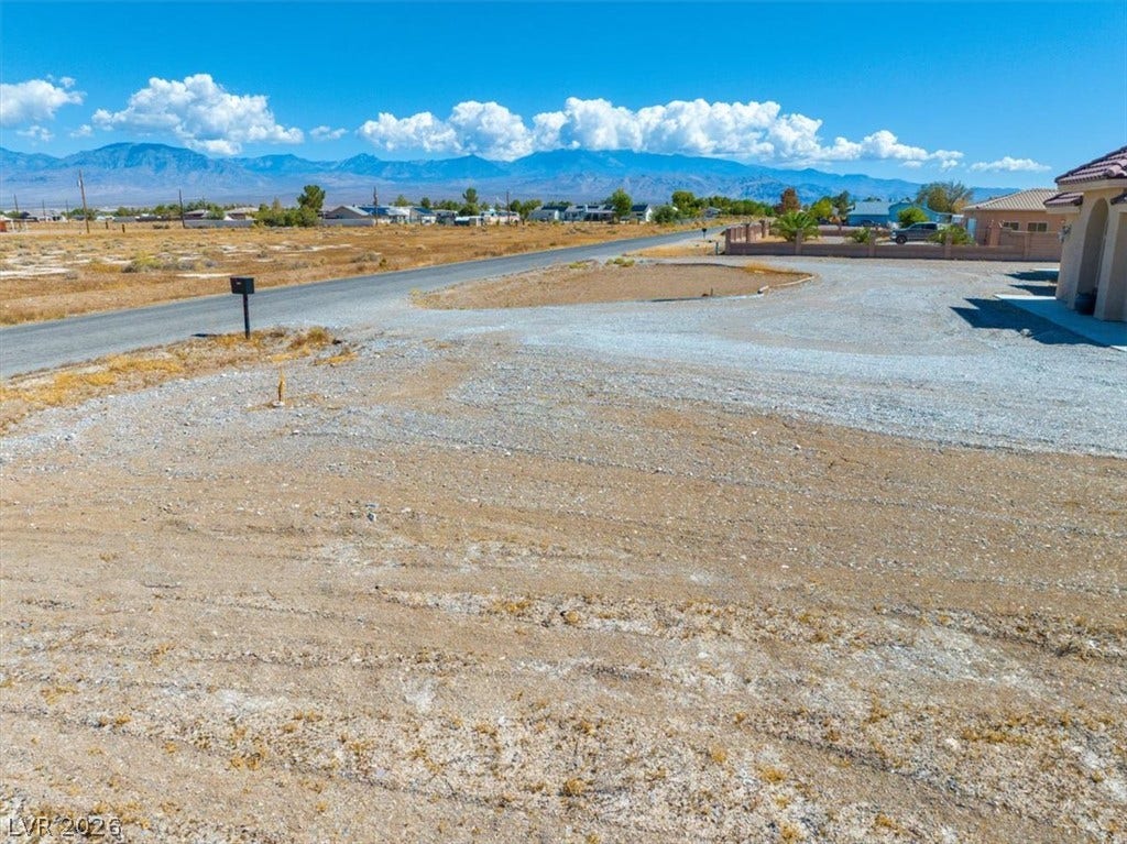 1641 W Huckleberry Street, Pahrump, NV 89048 Distant mountain peaks form a scenic backdrop beyond the level lot and paved road.