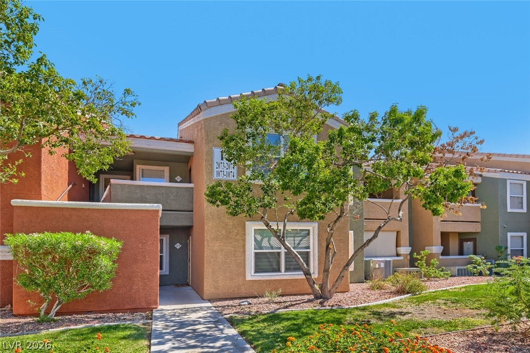 8101 W Flamingo Road, #1074, Las Vegas, NV 89147 A stucco exterior with tiled rooflines stands framed by mature green trees.