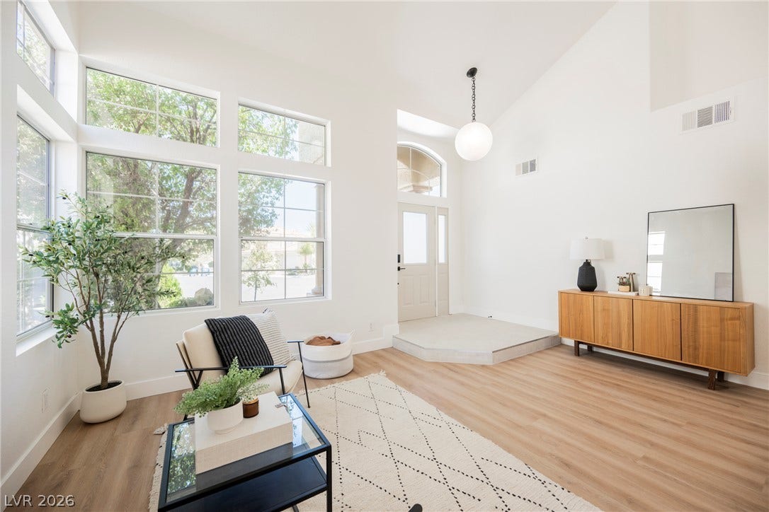 Soaring vaulted ceilings and tall windows frame this light-filled entrance area with wood-look flooring.