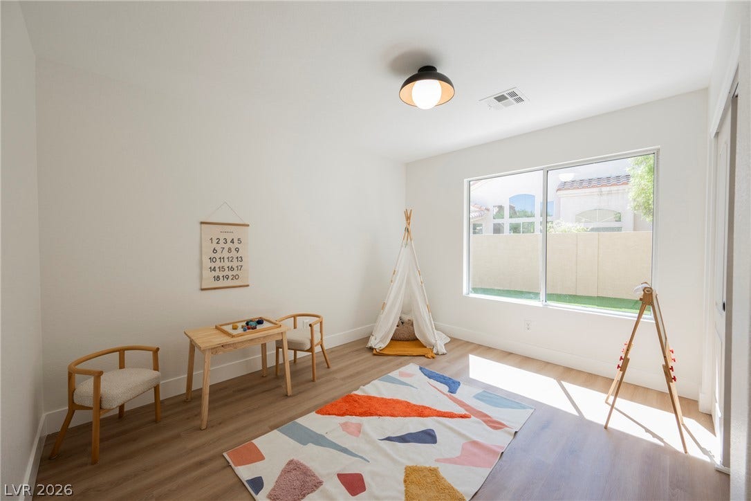 Natural light streams through a large window, highlighting smooth wood-plank flooring.