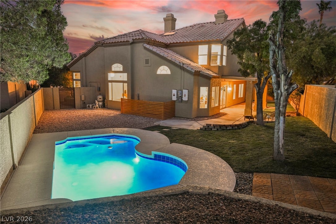 A sparkling in-ground pool and lush green lawn define this serene backyard retreat.