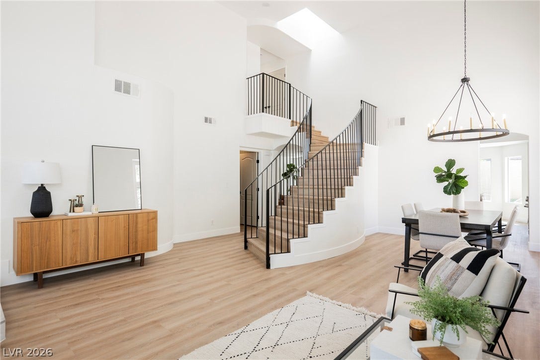 High ceilings and a sweeping staircase anchor this light-filled, open-concept living space.