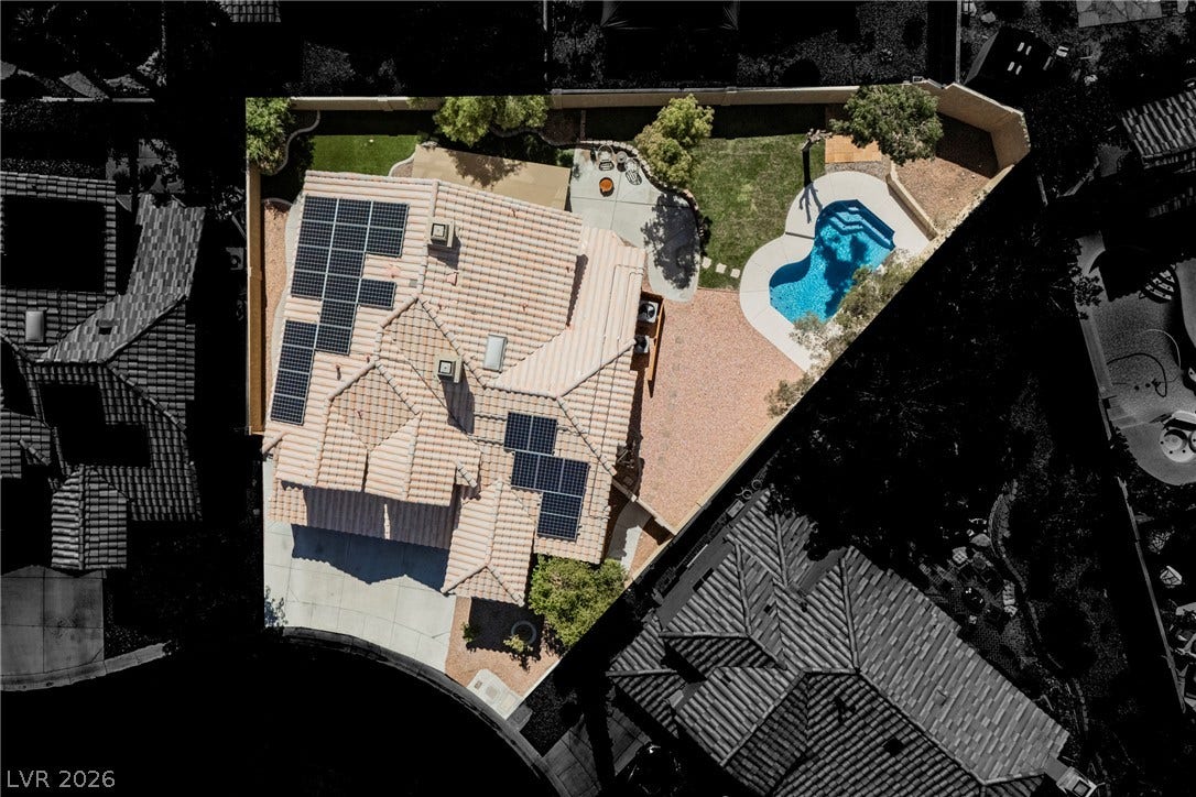 An aerial perspective reveals a tile roof with solar panels alongside a private pool.