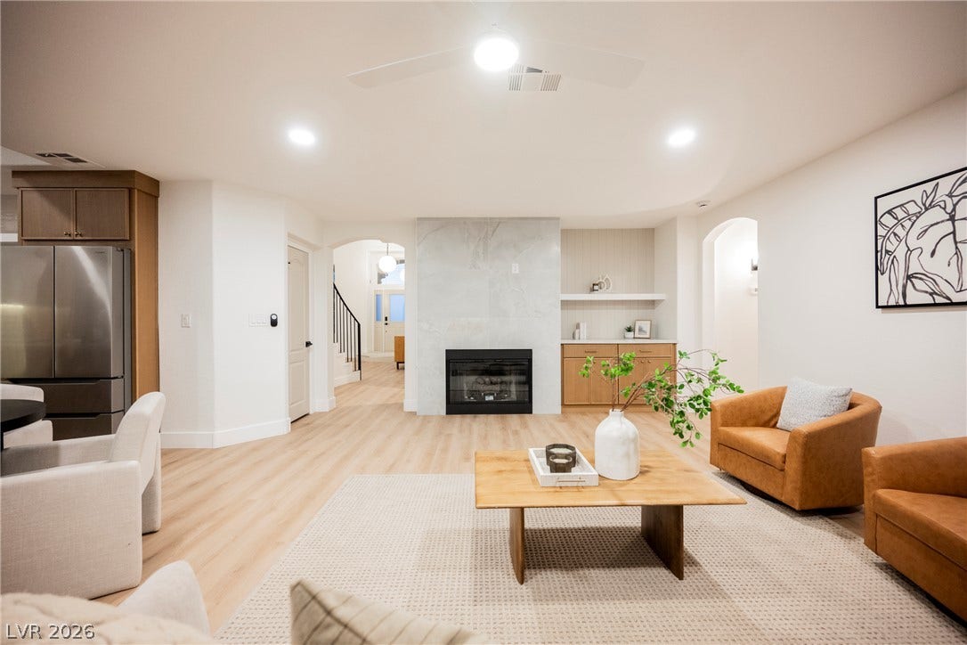 An open layout highlights a tiled fireplace and seamless light wood flooring throughout the living space.