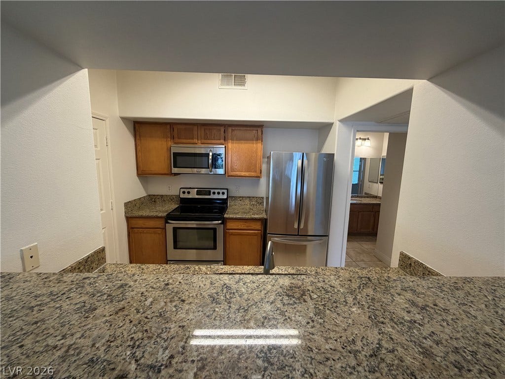 7255 W Sunset Road, #1167, Las Vegas, NV 89113 Rich granite countertops pair elegantly with classic wood cabinetry and modern stainless steel appliances.
