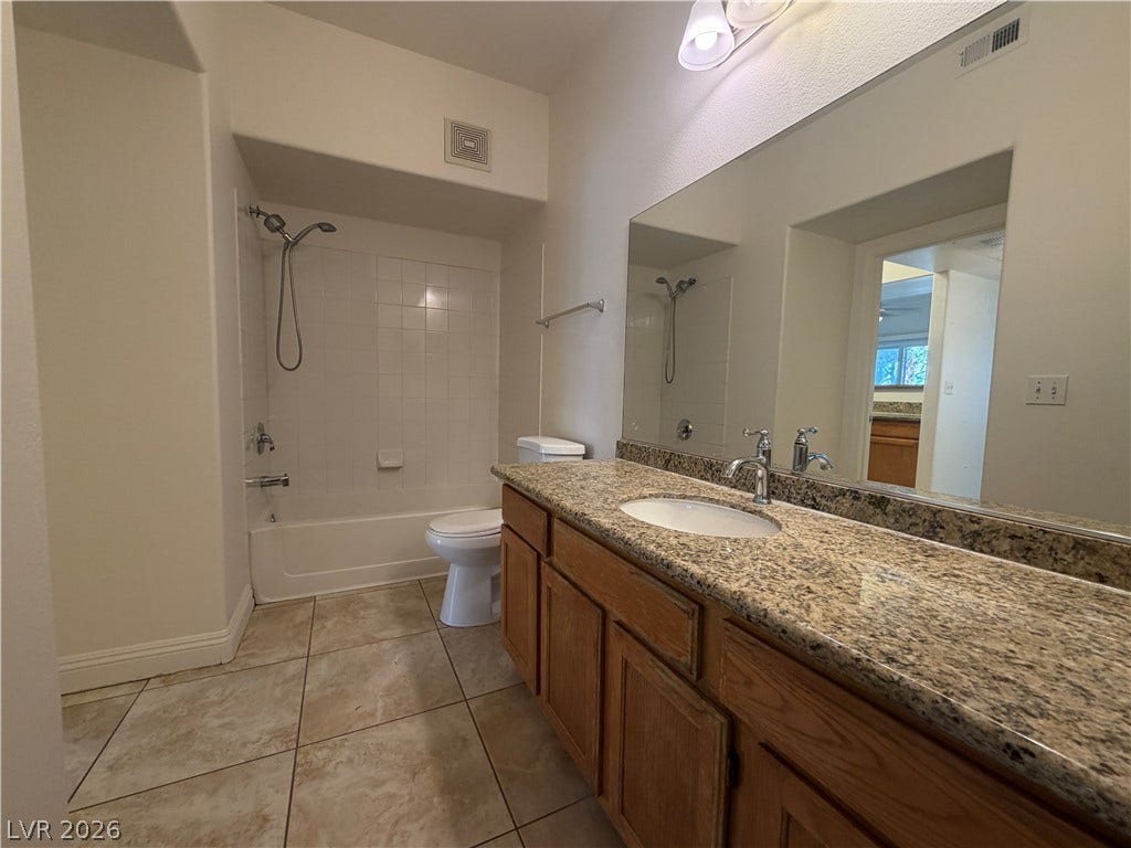 7255 W Sunset Road, #1167, Las Vegas, NV 89113 Warm wood cabinetry and granite countertops anchor this functional bathroom space.