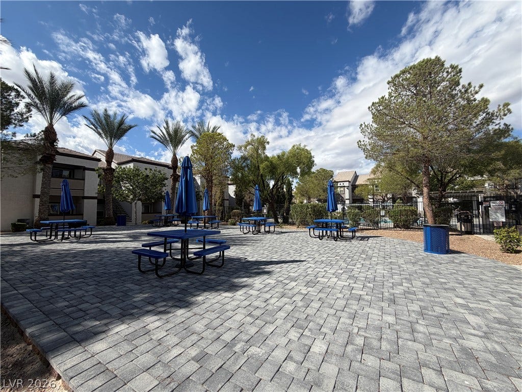 7255 W Sunset Road, #1167, Las Vegas, NV 89113 A spacious stone paver courtyard features shaded seating areas beneath towering palm trees.
