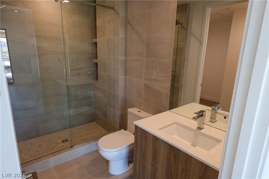 Floor-to-ceiling tiling and a glass-enclosed shower create a refined contemporary bath design.