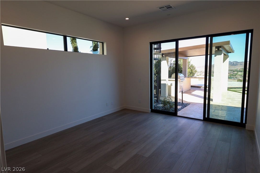 Sliding glass doors connect this minimalist space to a covered outdoor patio area.