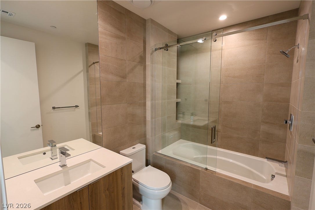 Floor-to-ceiling tiling and a glass-enclosed tub elevate this modern bathroom design.
