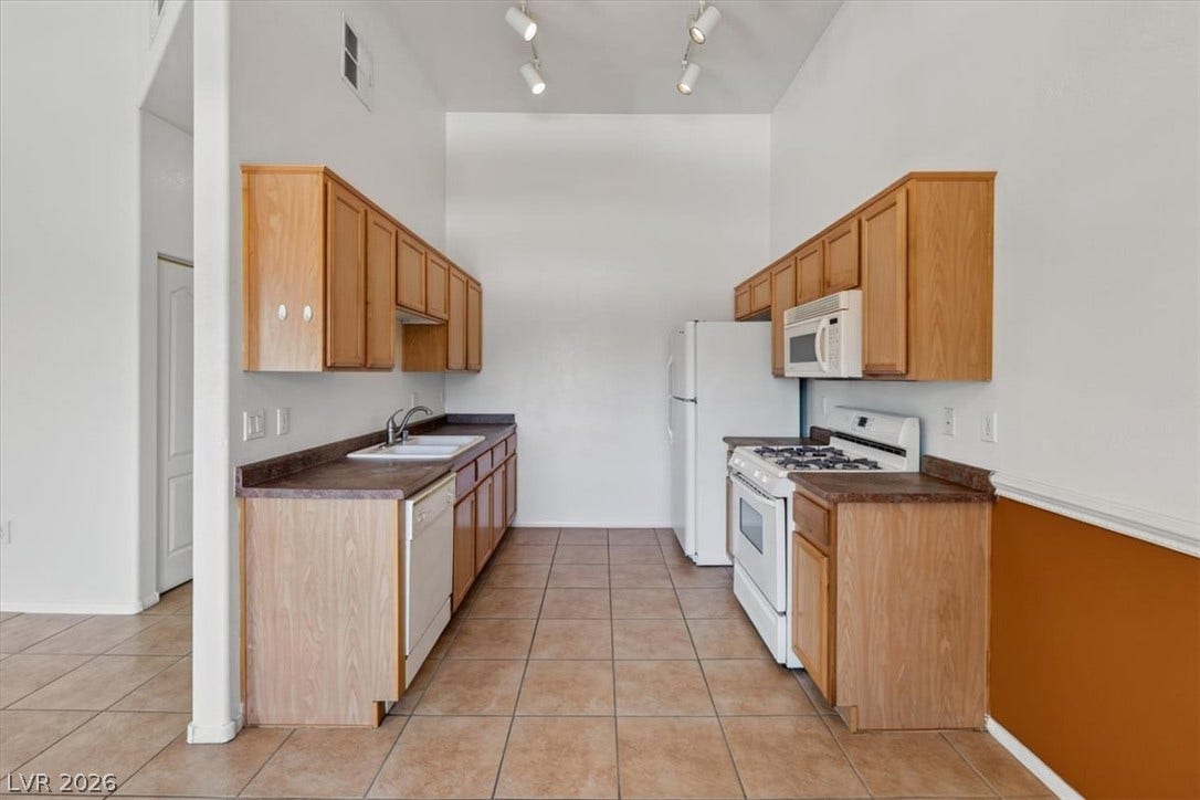 An efficient galley kitchen design showcases warm wood cabinets paired with durable tile flooring.