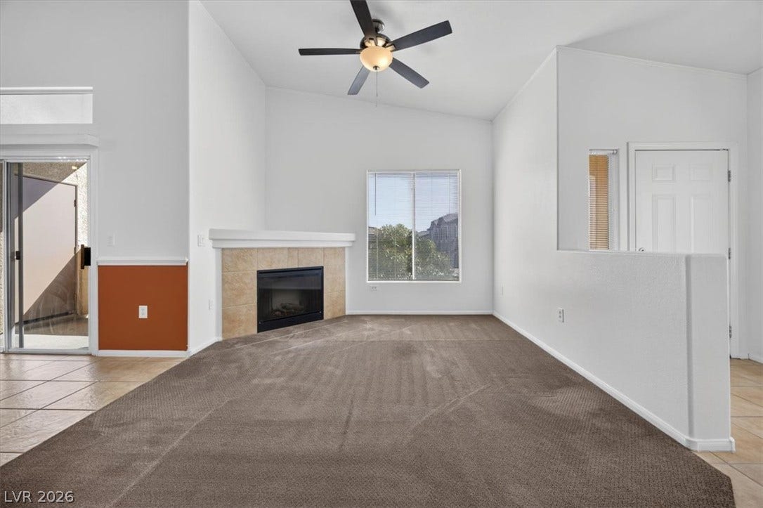 A corner tile-surfaced fireplace warms this open living area beneath vaulted ceilings.