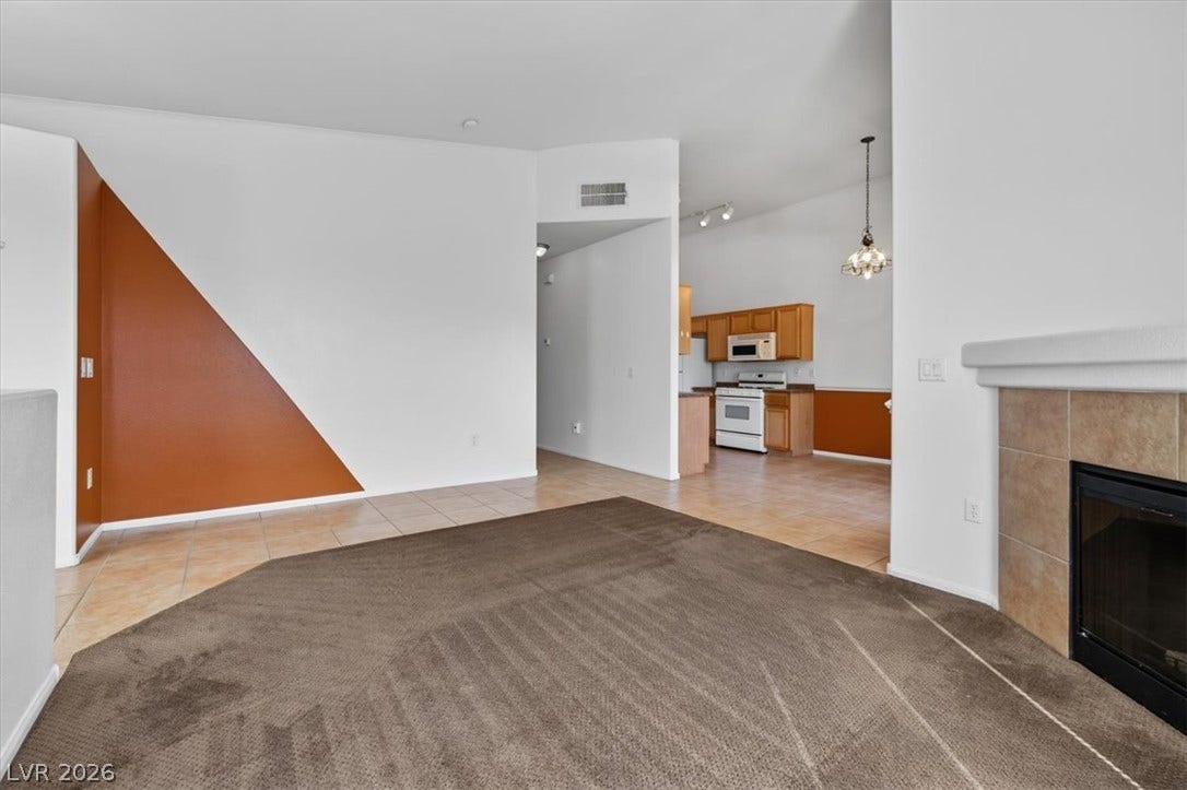 An open floorplan connects the carpeted living area with the tiled kitchen.