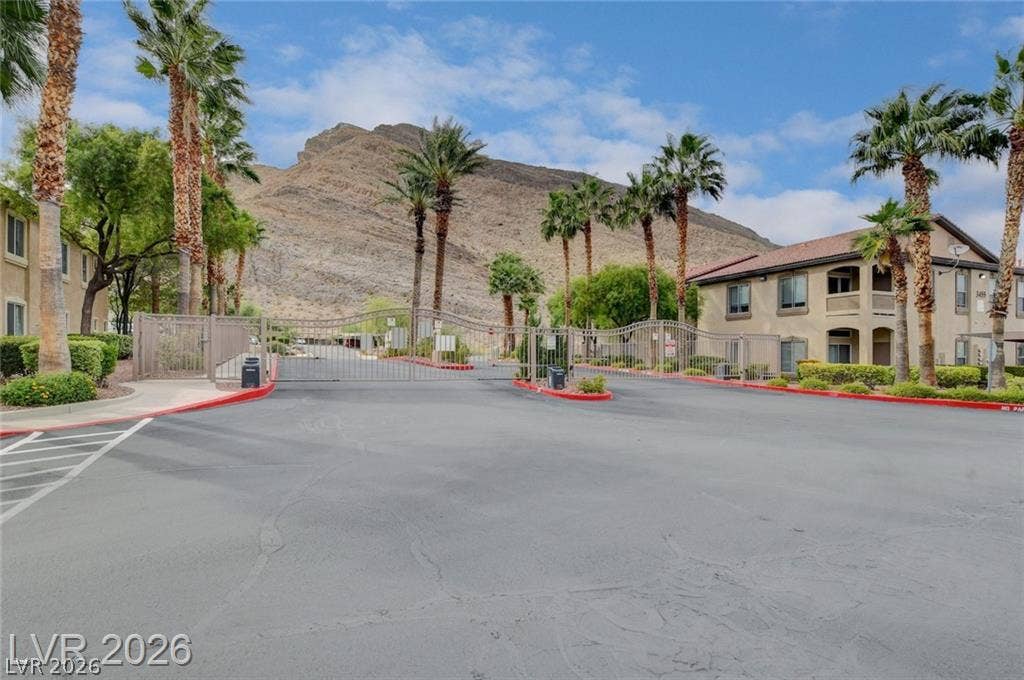 A secure gated entrance welcomes residents with majestic mountain views framed by towering palm trees.