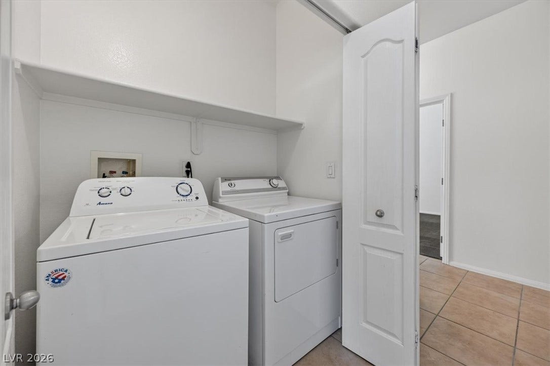 Tiled flooring and built-in shelving maximize utility in this dedicated laundry closet.