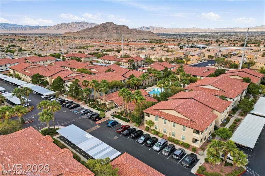 An aerial perspective showcases the tile roofs and community pool set against a mountain backdrop.