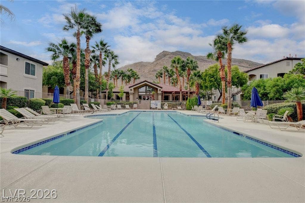 Palm trees frame a sparkling community swimming pool set against a dramatic mountain backdrop.