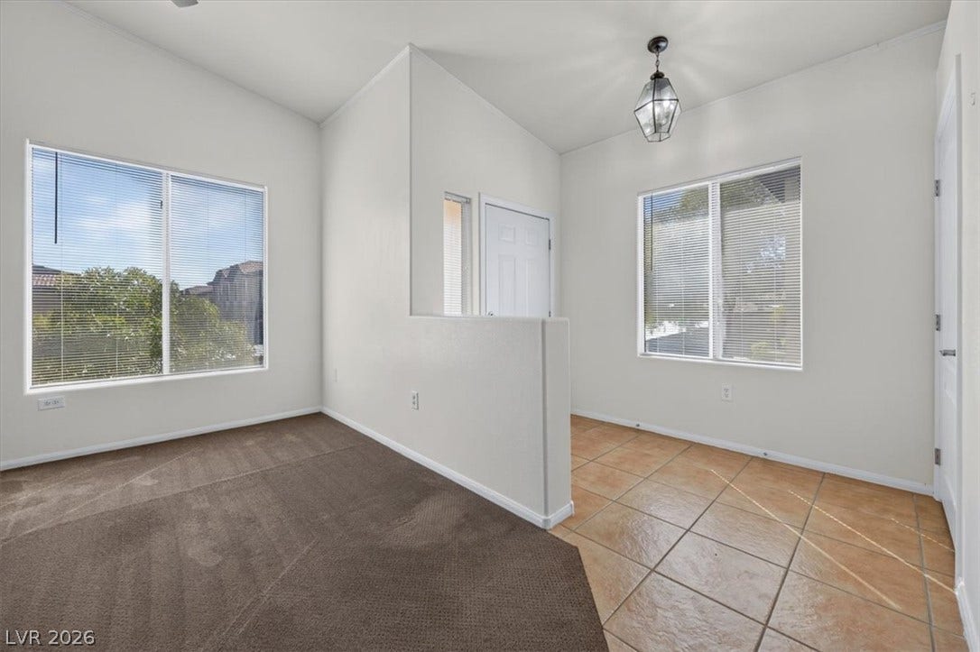 Tiled flooring and carpet define the open foyer beneath high ceilings and tall windows.