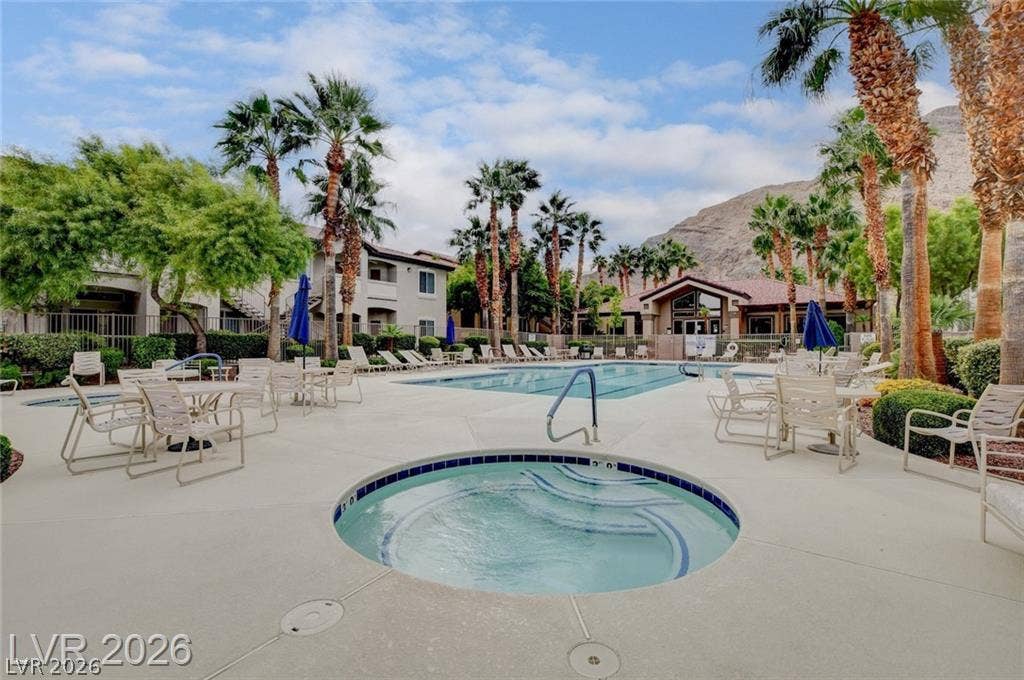 Lush palm trees and mountain backdrops frame a pristine outdoor pool and spa area.
