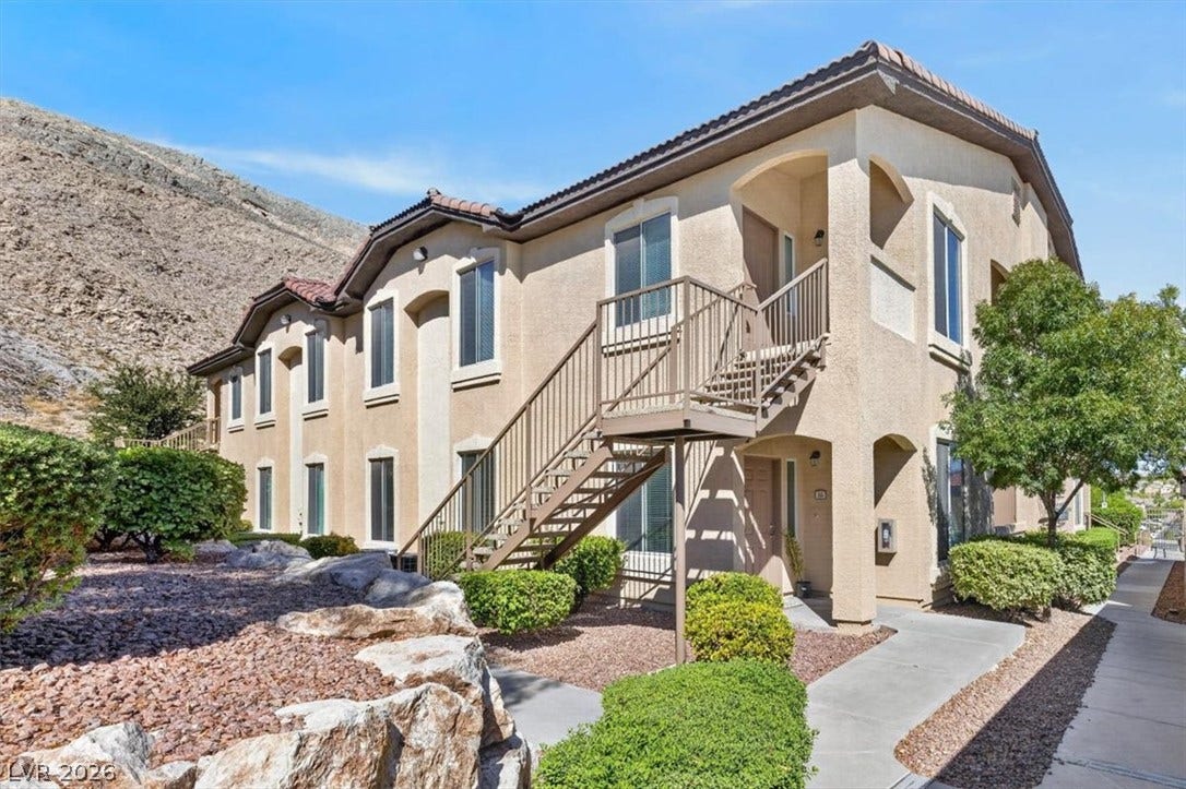 Multi-level residential exterior featuring classic stucco finishes and an outdoor staircase backdrop.