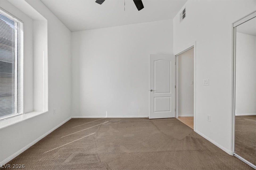 Plentiful natural light streams across carpeted flooring in this versatile bedroom space.