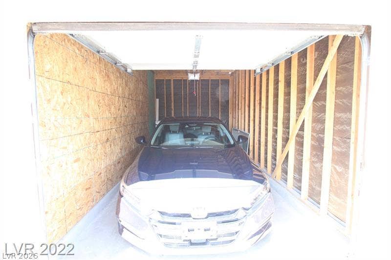 An enclosed garage bay features concrete flooring and open wood-framed wall studs.