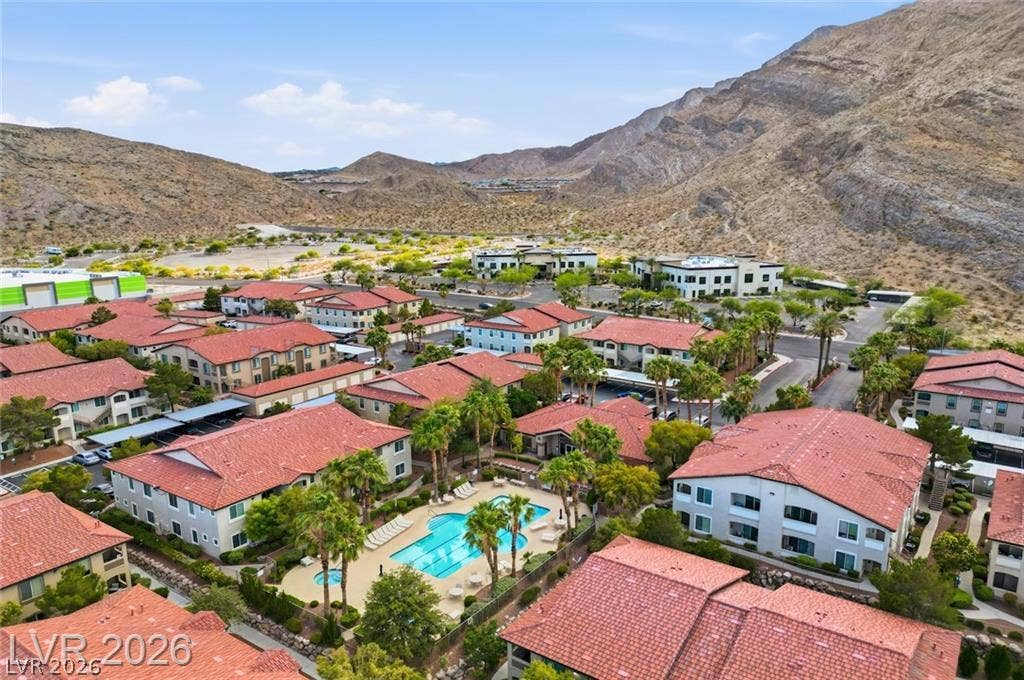 Dramatic mountain ridges frame a vibrant residential enclave featuring tile roofs and swimming pools.