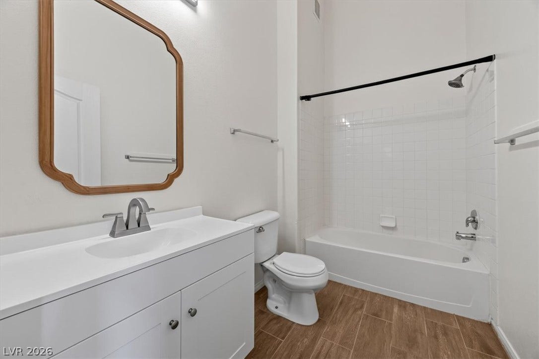 High ceilings and wood-look tile flooring elevate this modern bathroom featuring a clean white vanity.