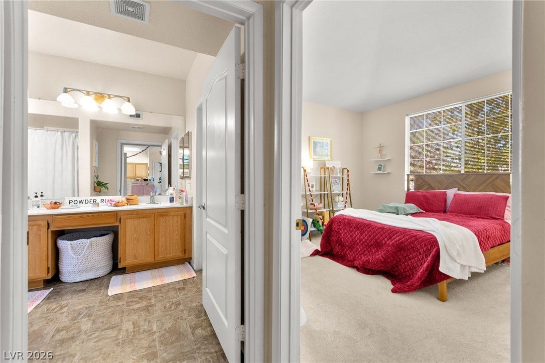 7628 Pacific Hills Avenue, #204, Las Vegas, NV 89128 A spacious bedroom sits adjacent to a private bathroom complete with a vanity setup.