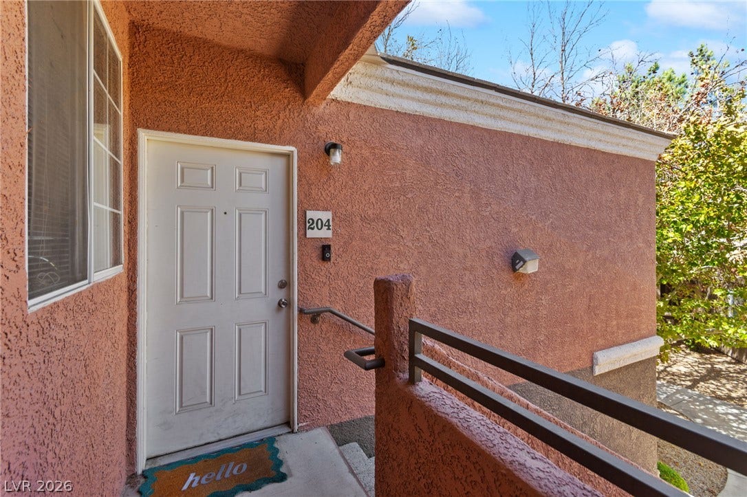 7628 Pacific Hills Avenue, #204, Las Vegas, NV 89128 Warm stucco walls frame a private covered entrance accessible by stairs.