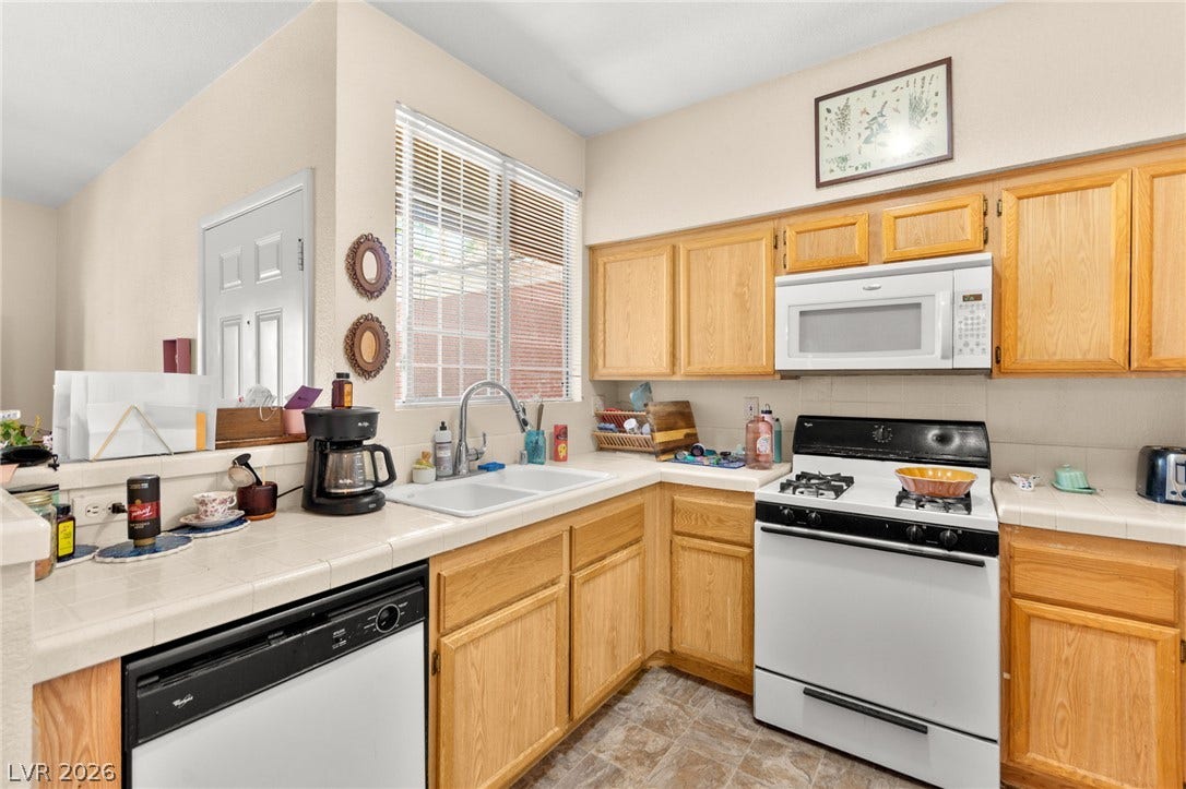 7628 Pacific Hills Avenue, #204, Las Vegas, NV 89128 Functional kitchen design showcases ample wooden cabinetry paired with tile countertops and built-in appliances.