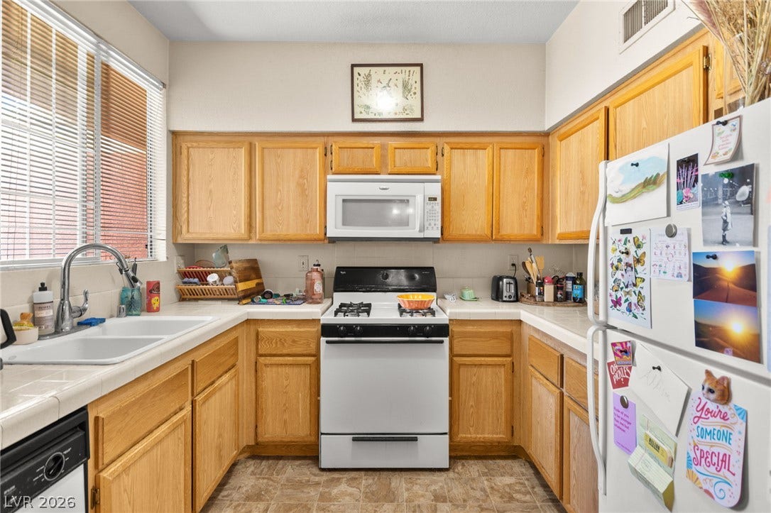 7628 Pacific Hills Avenue, #204, Las Vegas, NV 89128 Oak cabinetry and tile countertops frame this efficient kitchen layout equipped with a gas range.