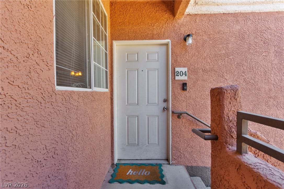 7628 Pacific Hills Avenue, #204, Las Vegas, NV 89128 Textured stucco walls surround a classic paneled front door leading into the residence.