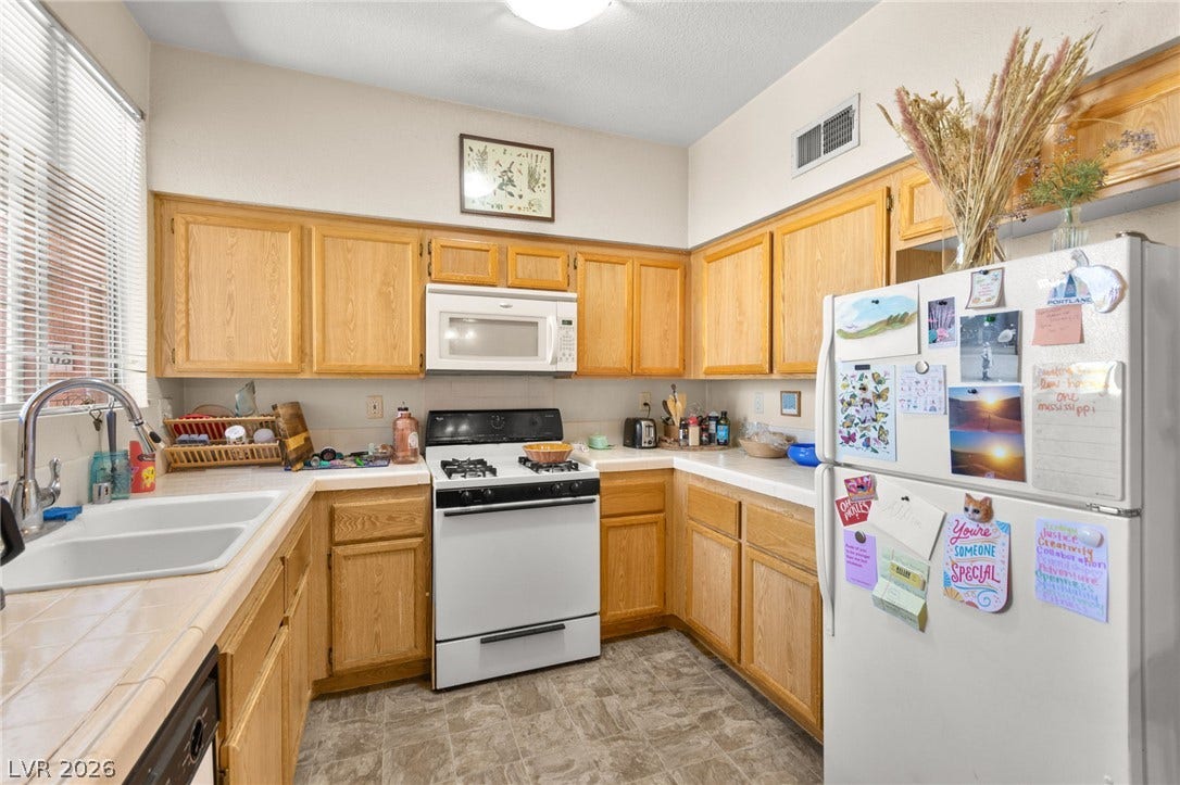 7628 Pacific Hills Avenue, #204, Las Vegas, NV 89128 Functional kitchen design showcases abundant wood cabinetry alongside durable tiled countertops and classic appliances.