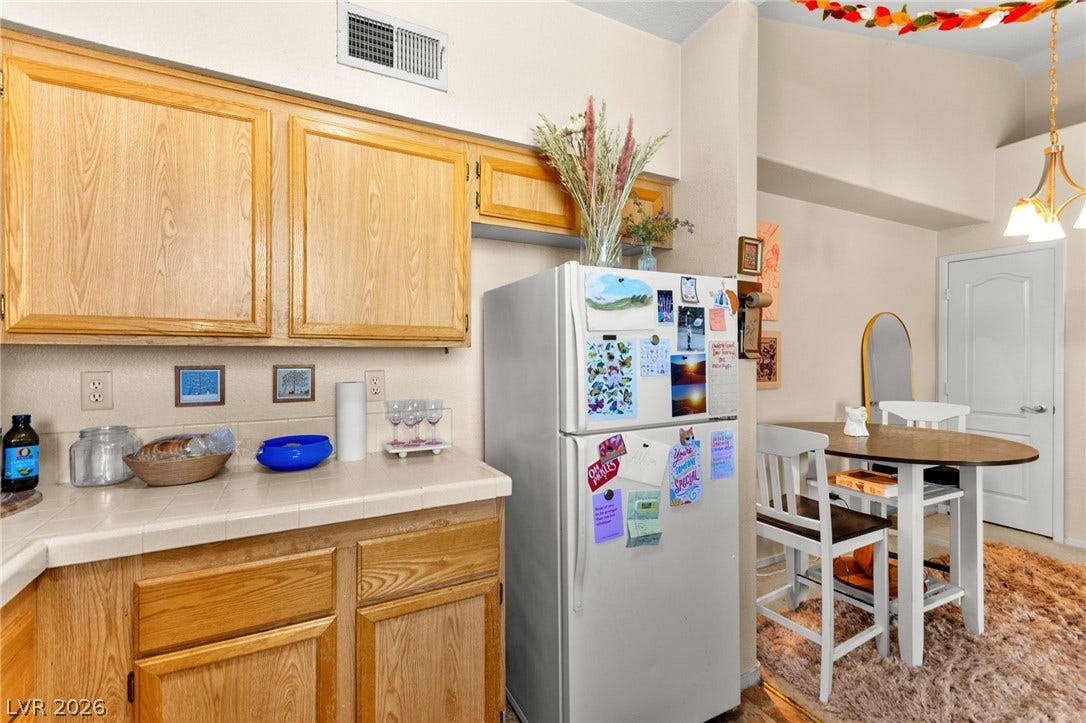 7628 Pacific Hills Avenue, #204, Las Vegas, NV 89128 Warm wood cabinetry and tile countertops flow seamlessly into an adjacent dining area.