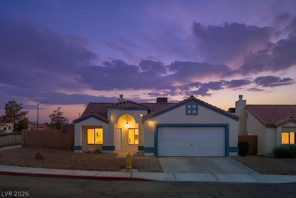 409 Groft Way, Henderson, NV 89015 Warm light glows from a southwest-style exterior featuring a tile roof and attached garage.