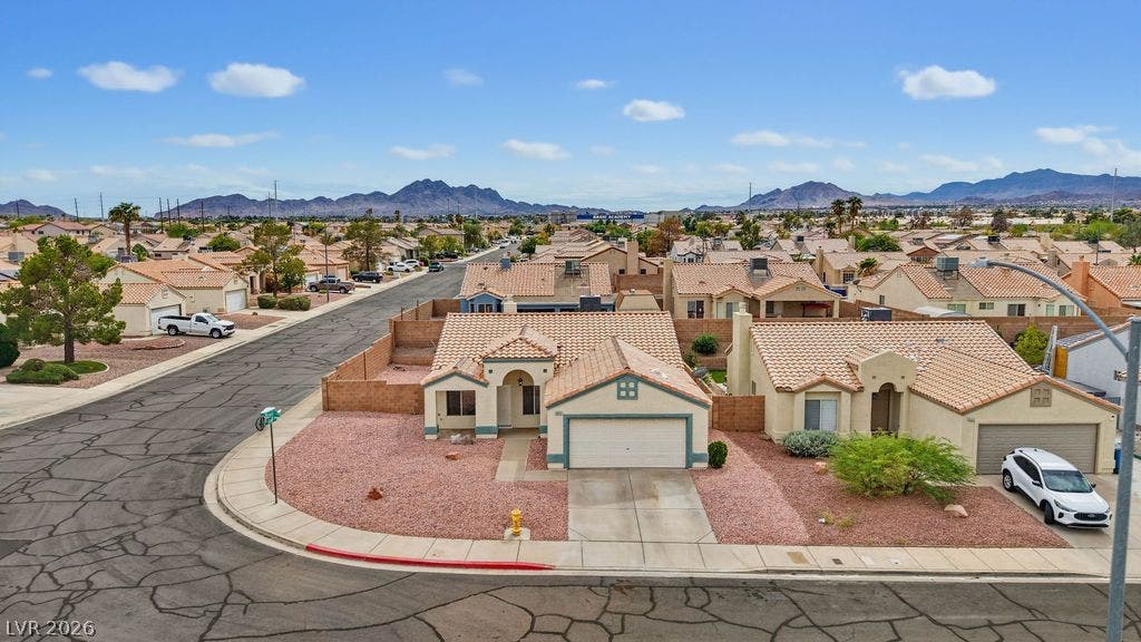 409 Groft Way, Henderson, NV 89015 A quiet residential street winds past single-story homes toward a dramatic mountain backdrop.