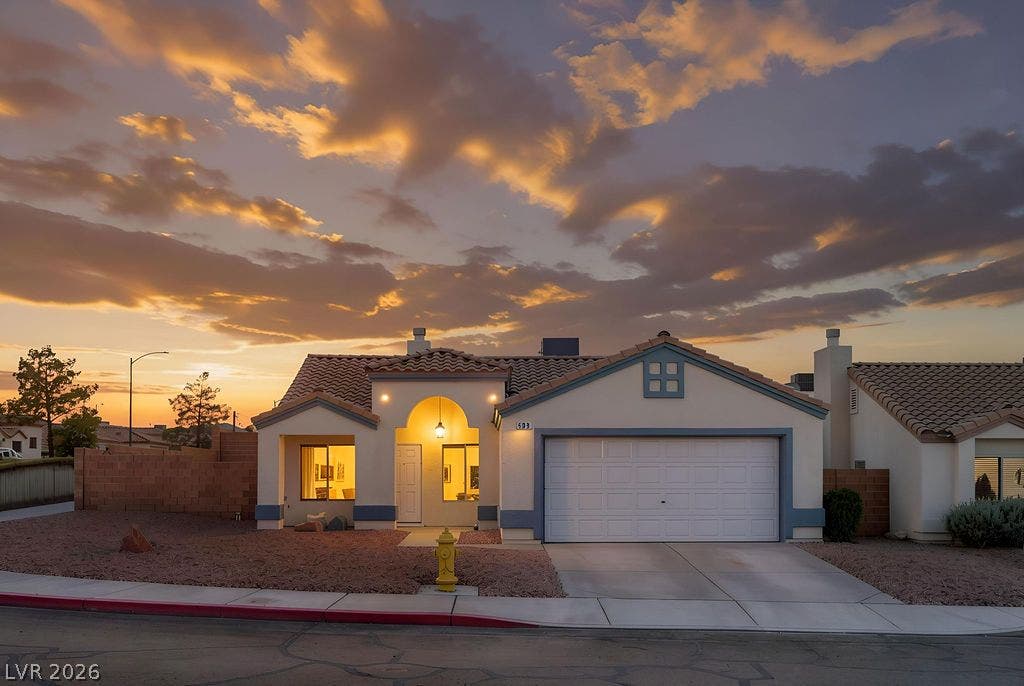 409 Groft Way, Henderson, NV 89015 A classic stucco exterior sits under a tiled roof with an integrated garage and arched entryway.