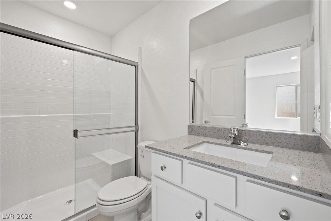 6724 Violet Cascade Avenue, Las Vegas, NV 89156 Clean lines and a stone-topped vanity define this modern bathroom with a glass-enclosed shower.