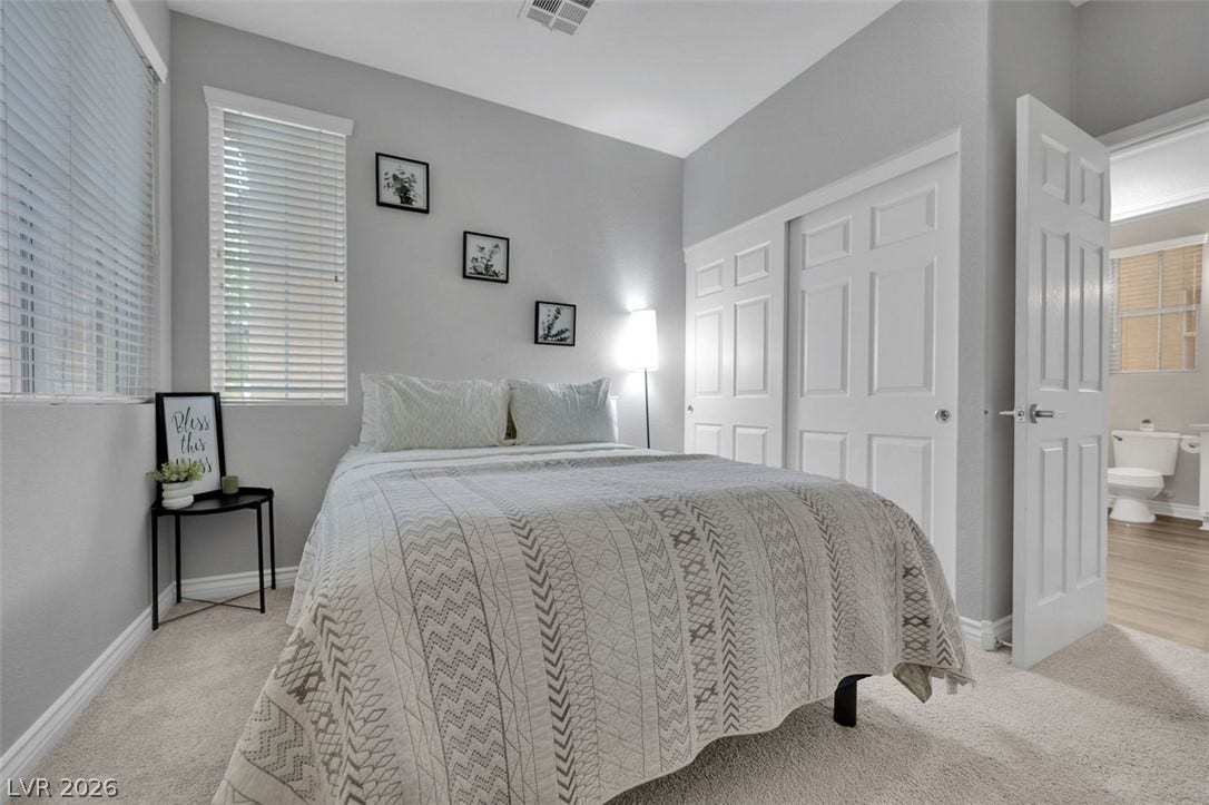 Plush carpeting anchors this serene bedroom featuring tall ceilings and crisp white woodwork.