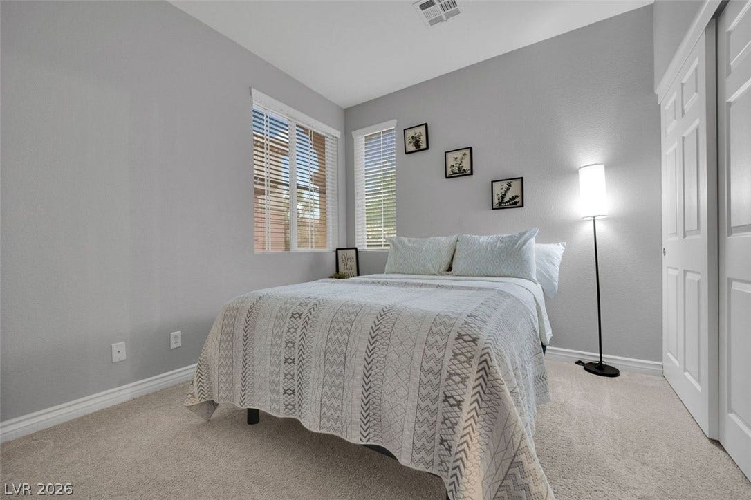 Plush carpeting and dual windows create a serene, well-lit atmosphere in this modern bedroom.