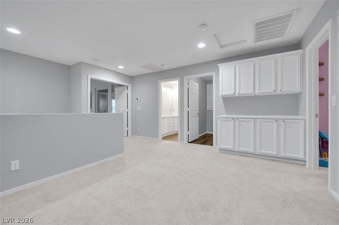 A versatile upstairs loft displays plush carpeting alongside built-in cabinetry storage.