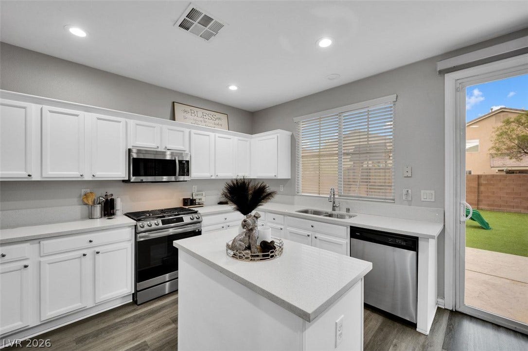 White cabinetry paired with stainless steel appliances surrounds a central island workspace.