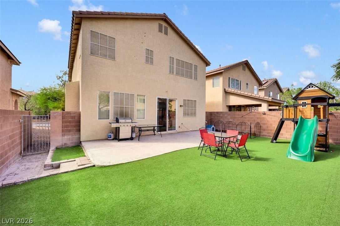 A spacious backyard features a concrete patio and low-maintenance turf grass.